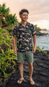 Man on lava rocks in the Pink Flamingo Hibiscus Hawaiian shirt in black with green shorts