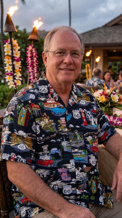 Man seated at a luau in the Route 66 Travel Sights Hawaiian shirt in black